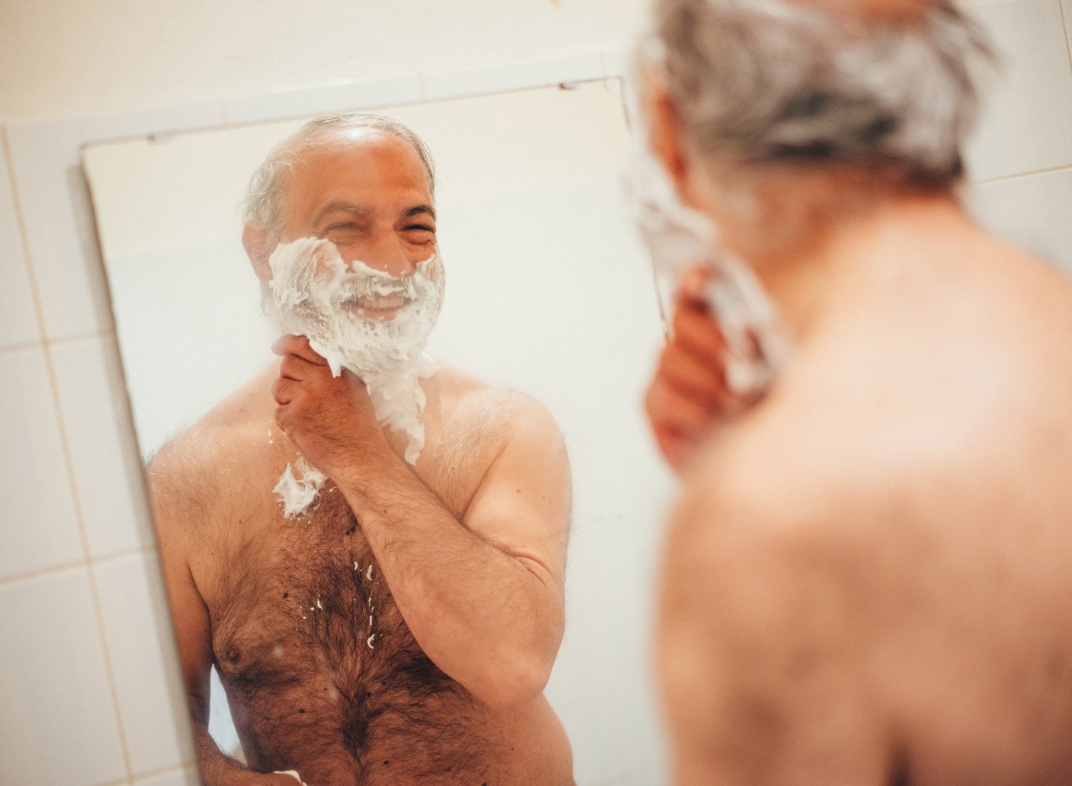 Une personne sans abri se rase face à un miroir de l'accueil de jour